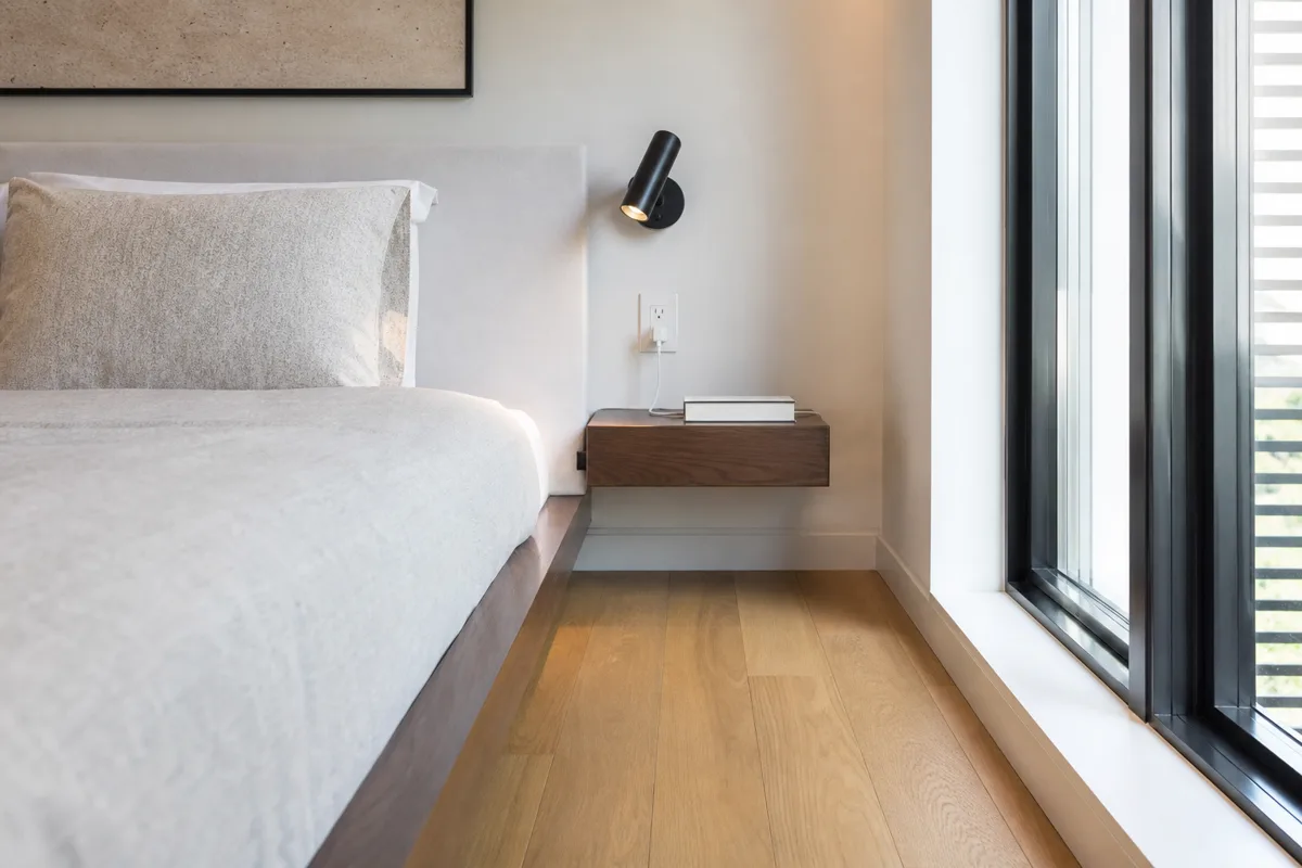Wall-mounted floating shelf nightstand in a narrow bedroom
